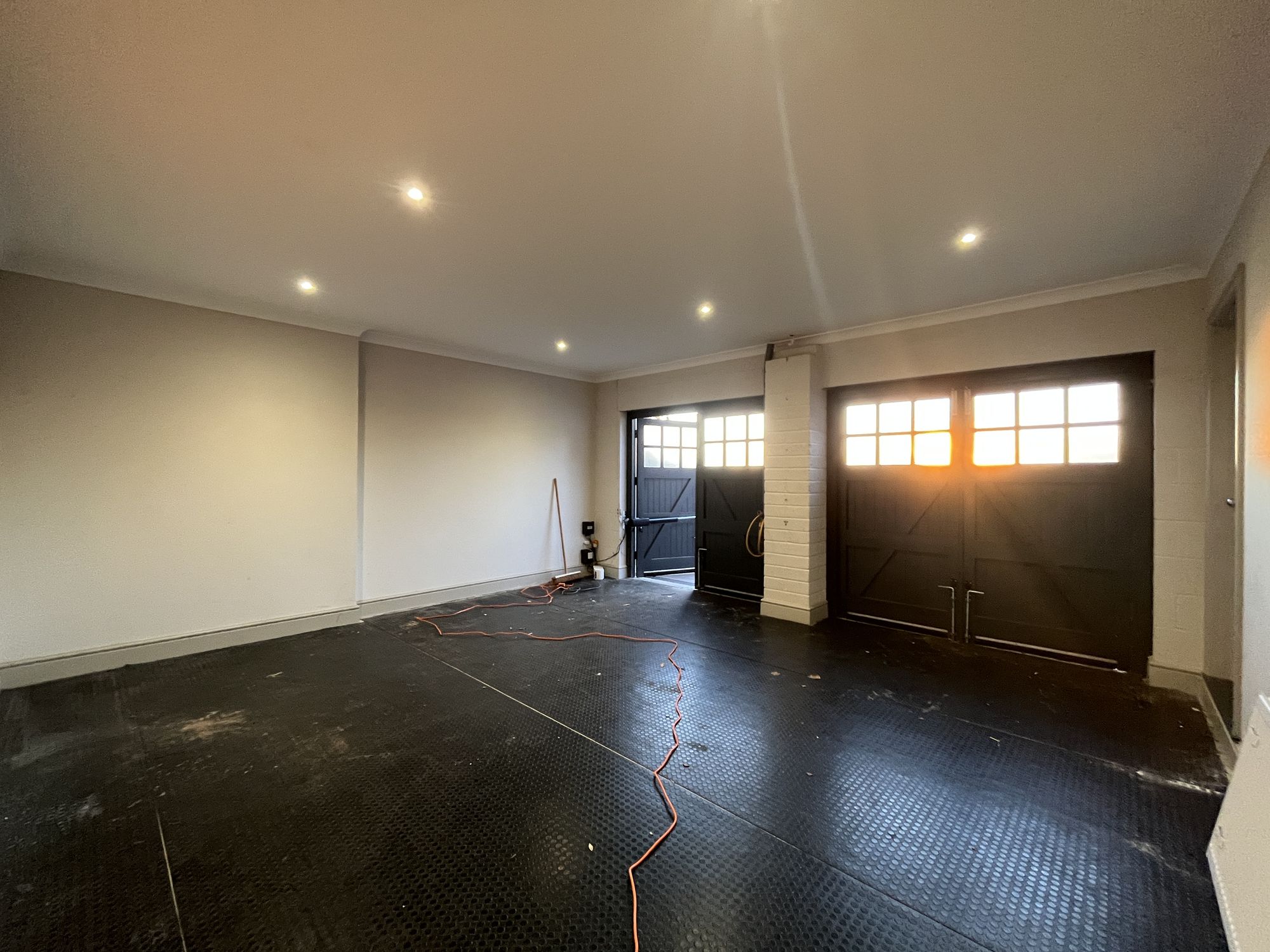 The space as a garage at the start, with the original black carriage doors and bare floor