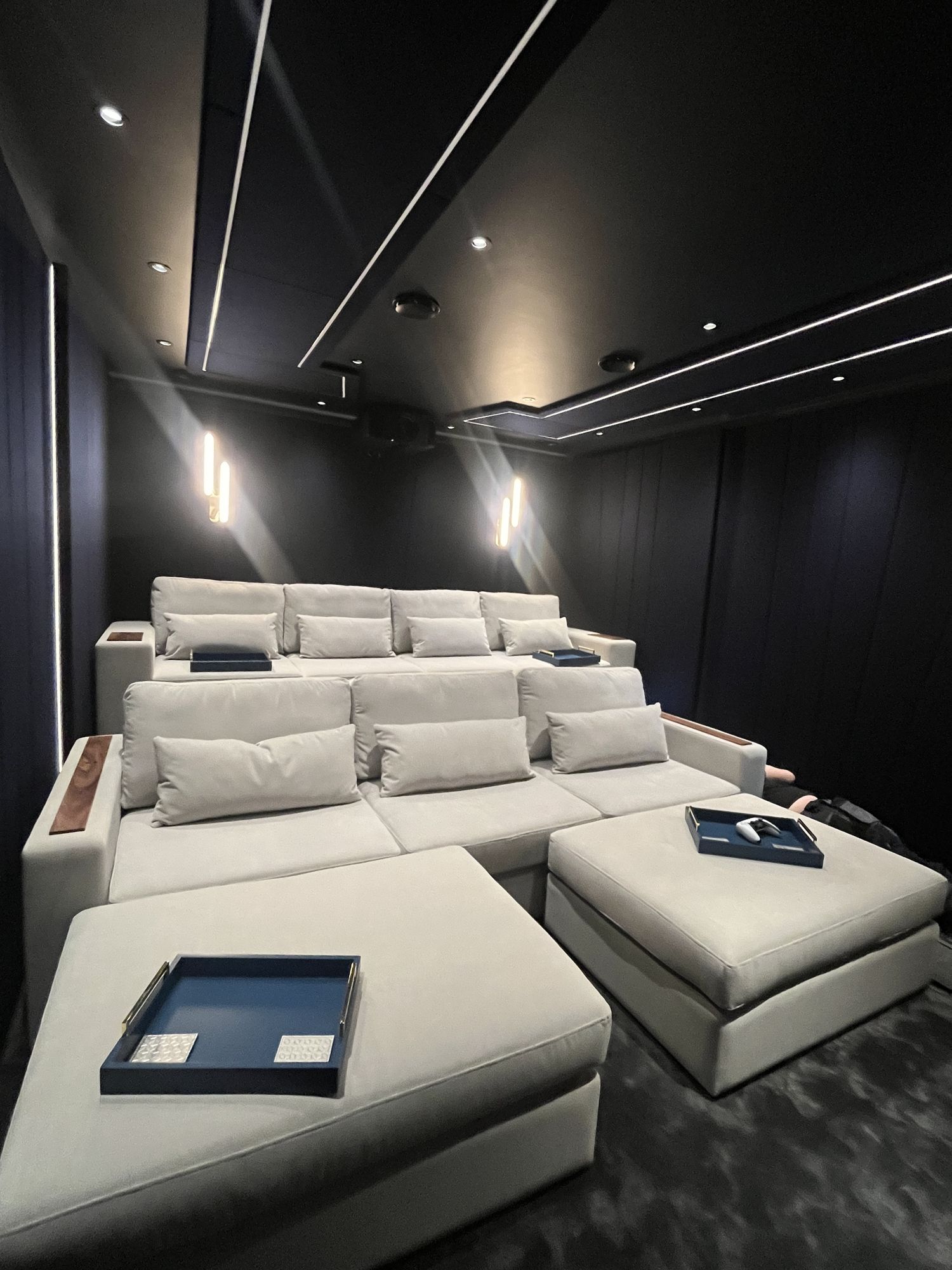 The two tiered rows of seating seen from the front corner, navy walls and lit ceiling raft above