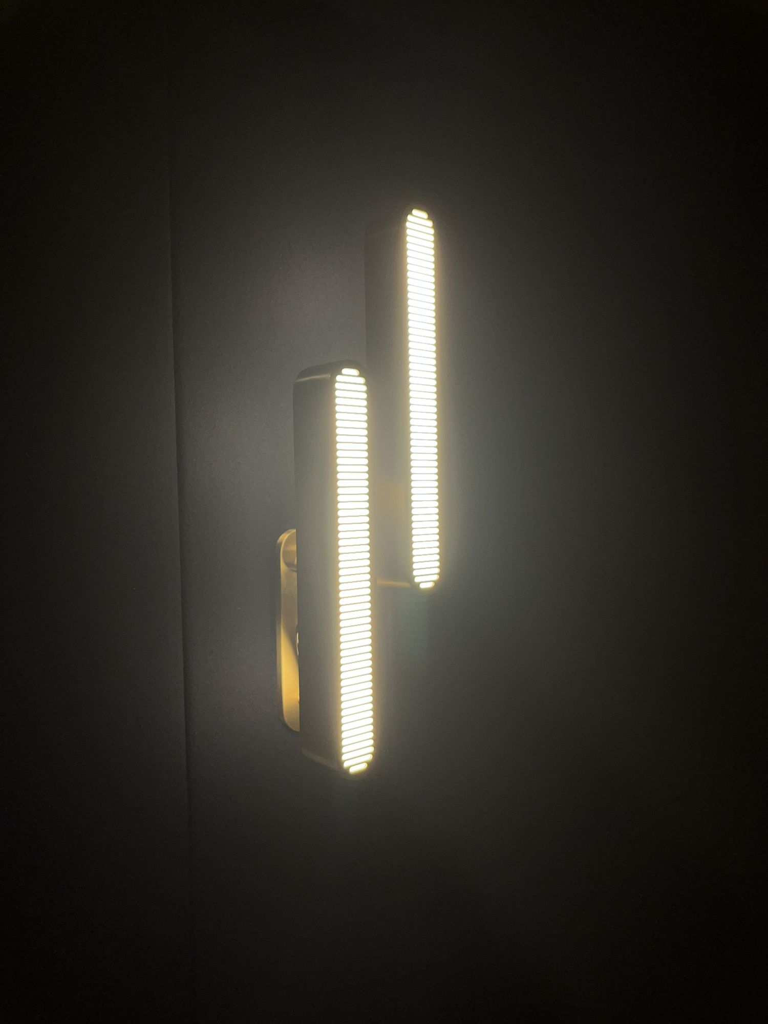 A brass wall sconce lit against the navy panelled wall