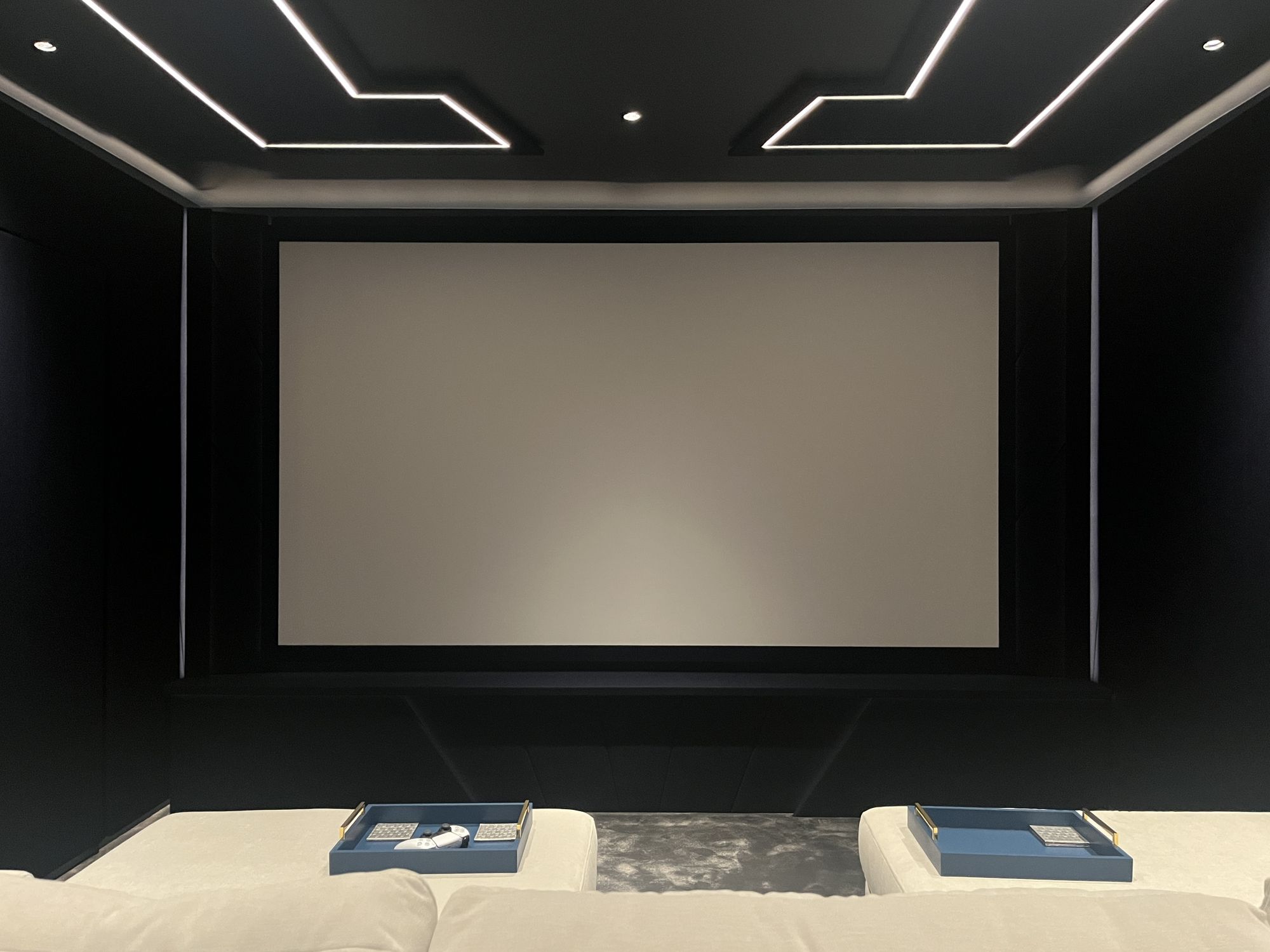 The screen wall set into navy panelling, with the upholstered base below